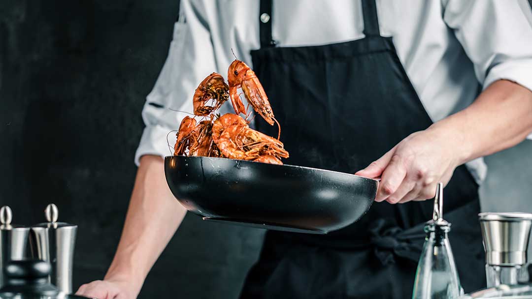Person flipping seafood in pan