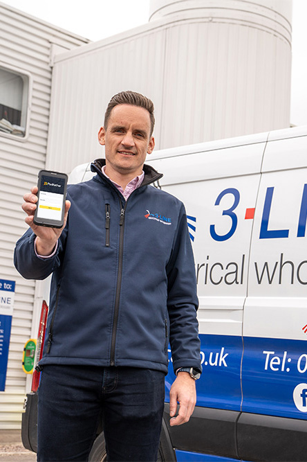 Man in a blue jacket standing in front of a van holding a mobile phone