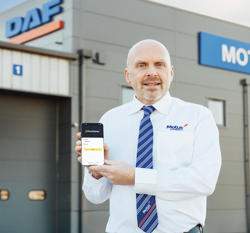 Smiling man in a white shirt and blue stripped tie holding a mobile device