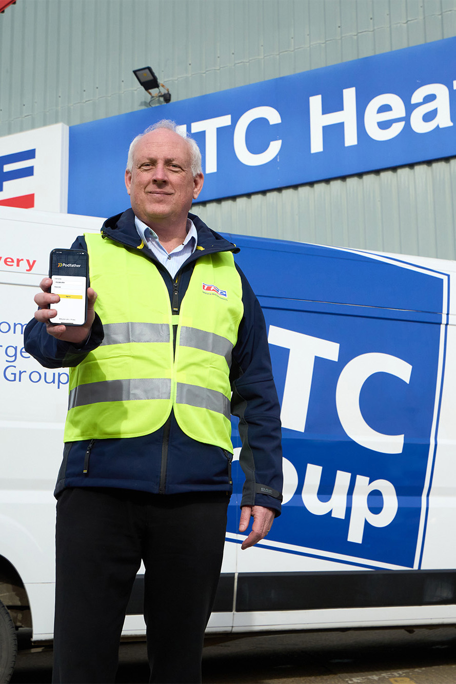 Man in a high vis standing in front of a van holding a mobile phone